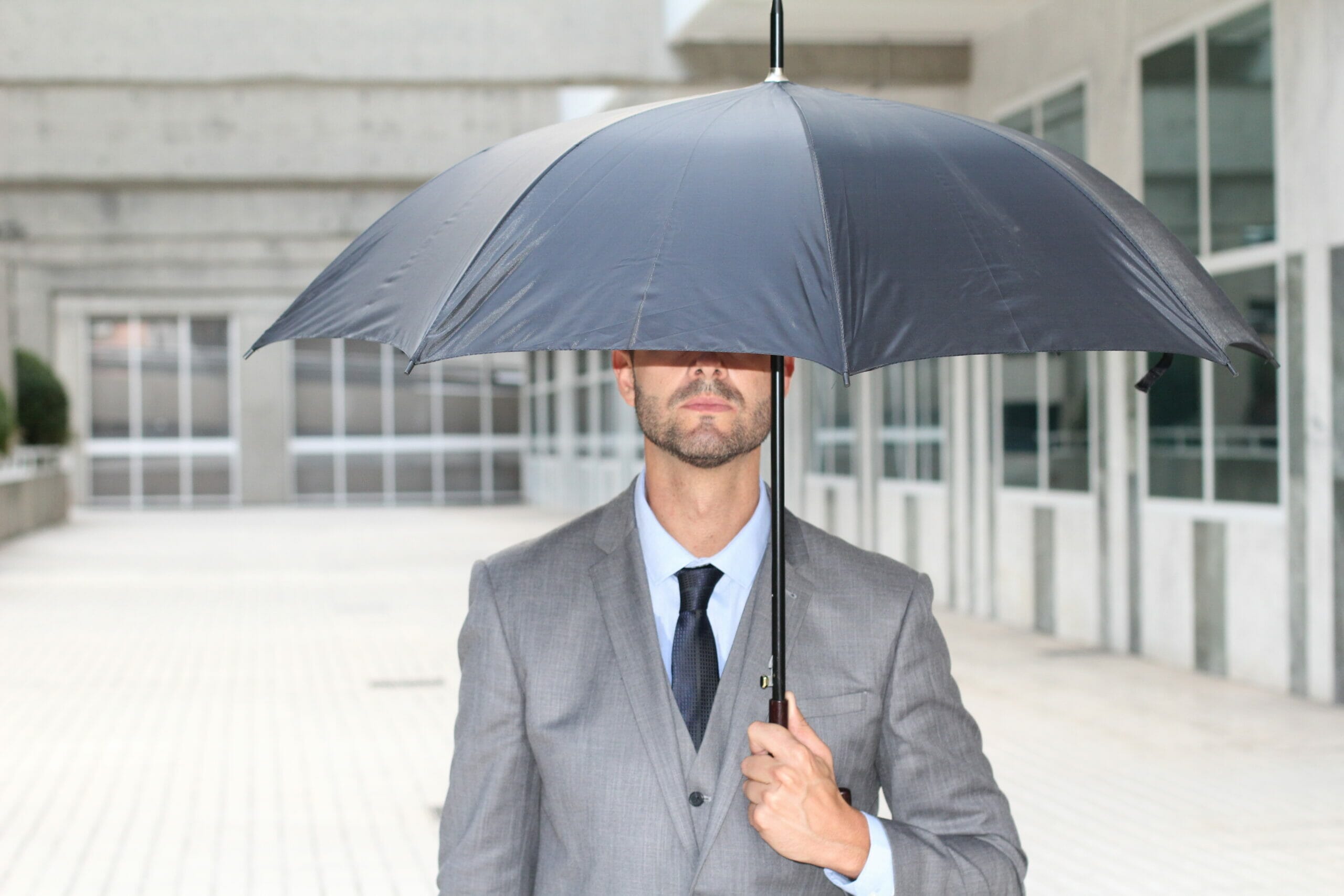 businessman hiding under an umbrella in office 878389744 5184x3456 1 scaled
